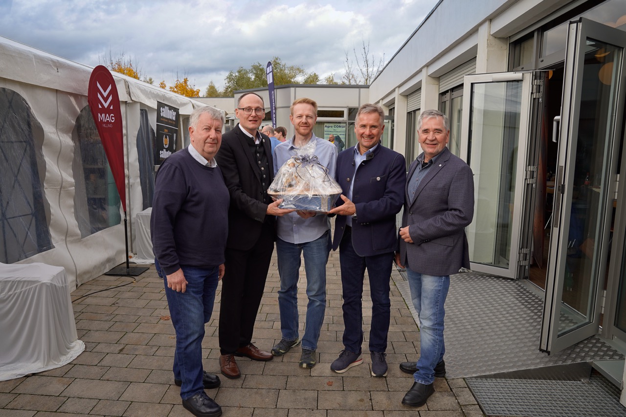 Fünf Männer halten ein Geschenk hoch