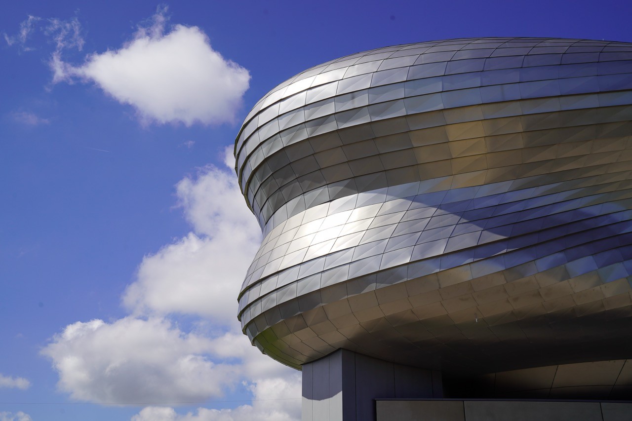 Die silberfarbende und wolkenartige Außenform des Paneum vor einem blauen Himmel und Wolken.