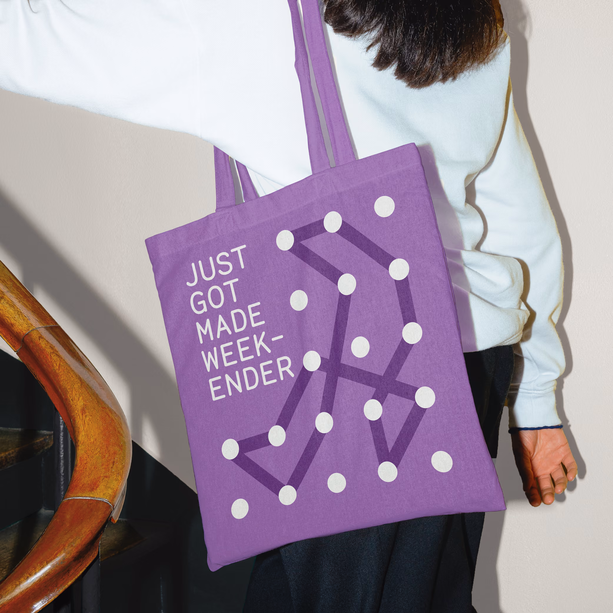 Lady walking holding a tote bag for an event called 'Just Got Made Weekender'.