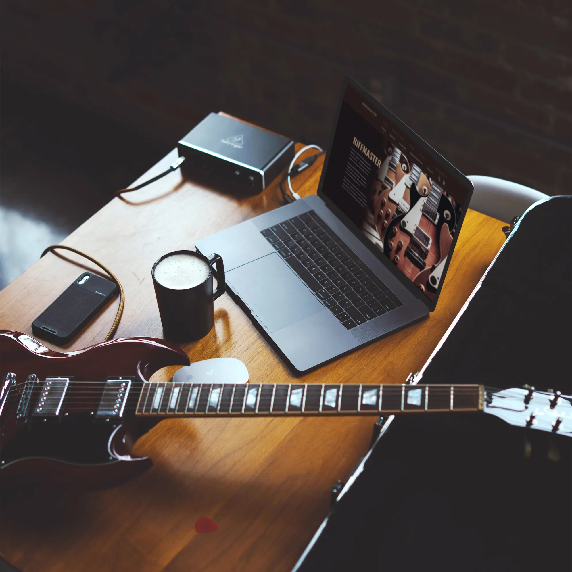 An office table with laptop, electric guitar and mug of coffee on it in a brown vintage style.