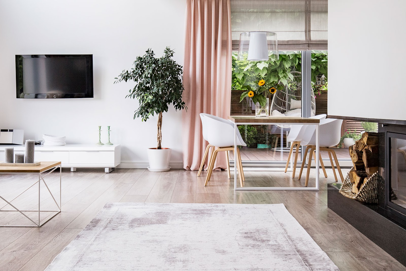 Modern living room with timber floor boards, white walls, pink s-fold curtains and a fireplace.