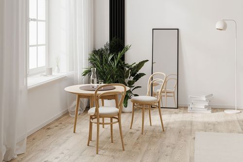 A small dining area with a round table sits atop hybrid flooring that combines laminate and a rug. The layered textures add warmth and define the cozy eating space.