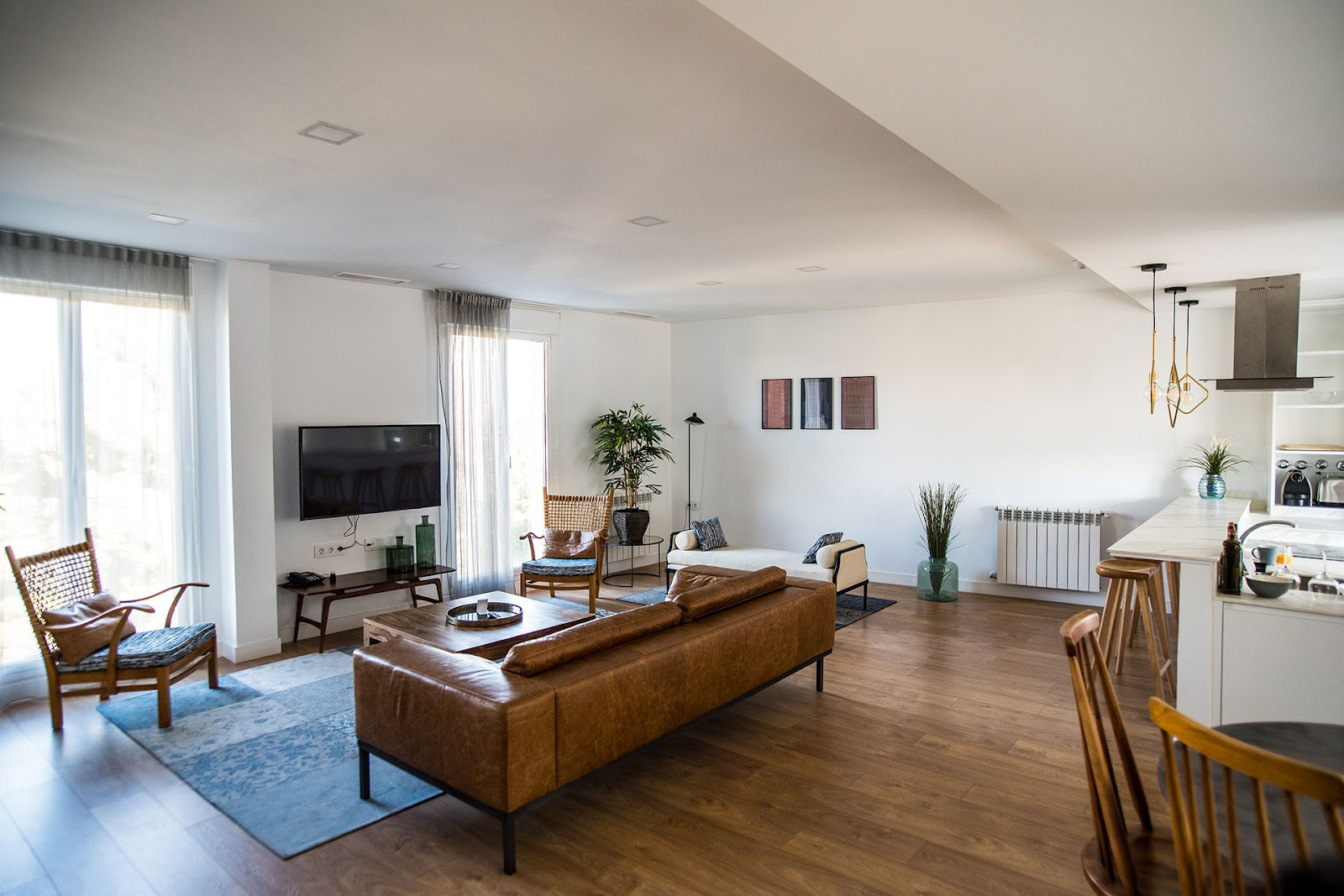 Open plan living area with timber flooring, leather lounge, timber occasional chairs and modern art and finishings
