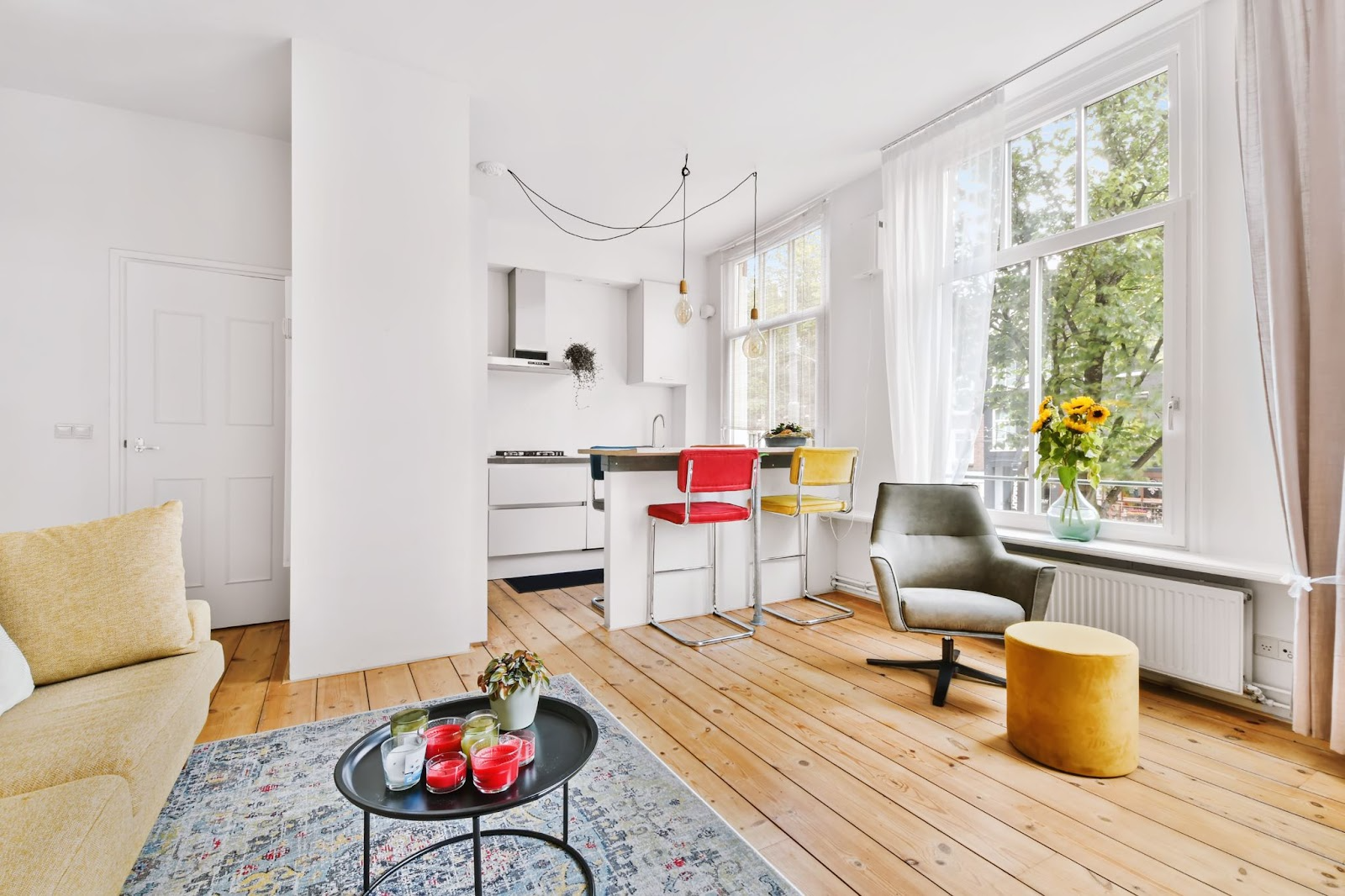 Bright apartment with white walls, timber floorboards, and colourful chairs.