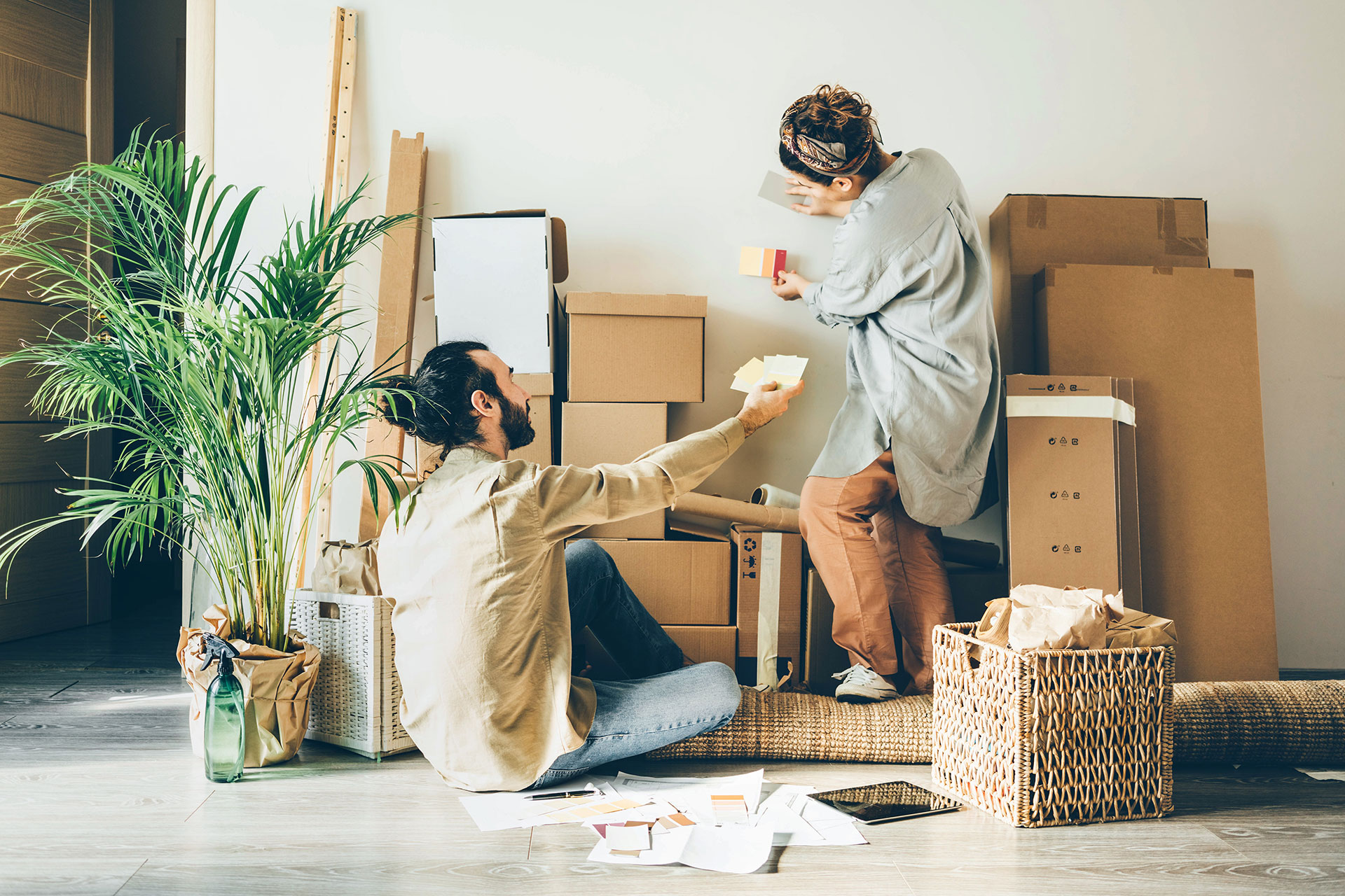 Couple compares wall colour samples while sitting on hybrid flooring in a bright, modern room. Highlights the versatility and design options of hybrid flooring.