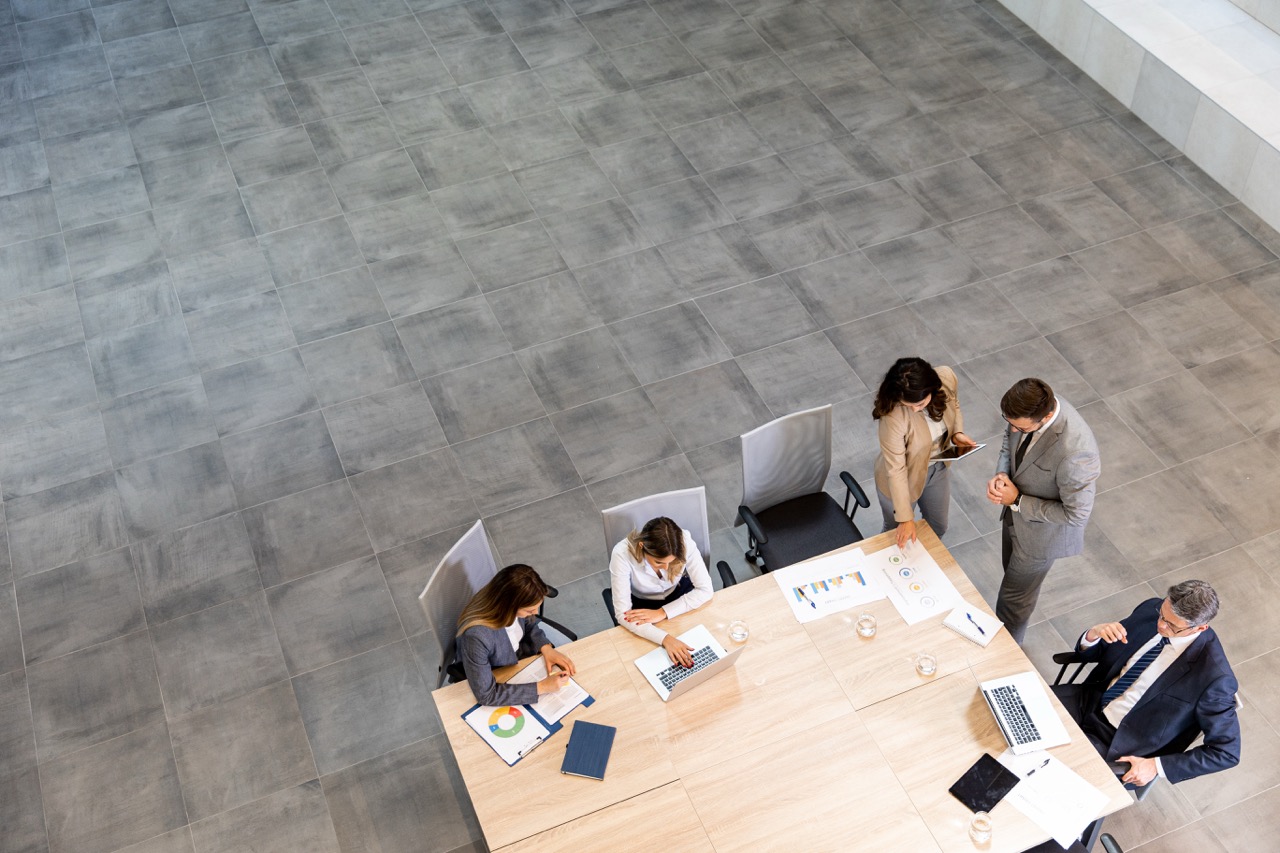 Group of business professionals having a discussion in a modern office workspace with carpet tile flooring.