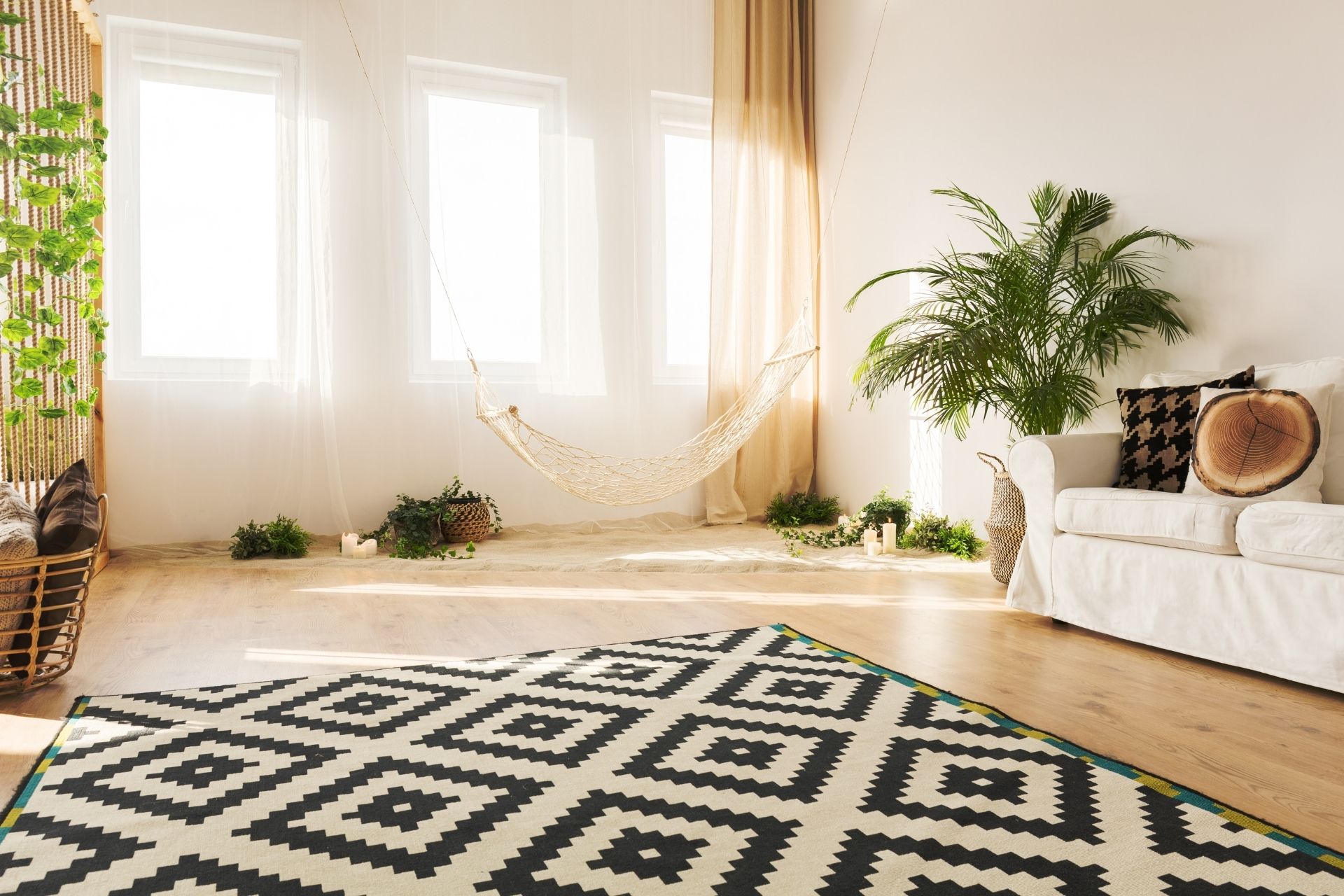 Bright boho-style living room featuring a bold black-and-white diamond patterned carpet over light hardwood floors.