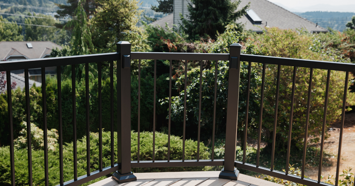Modern black aluminum railing with vertical balusters framing a scenic backyard outlook