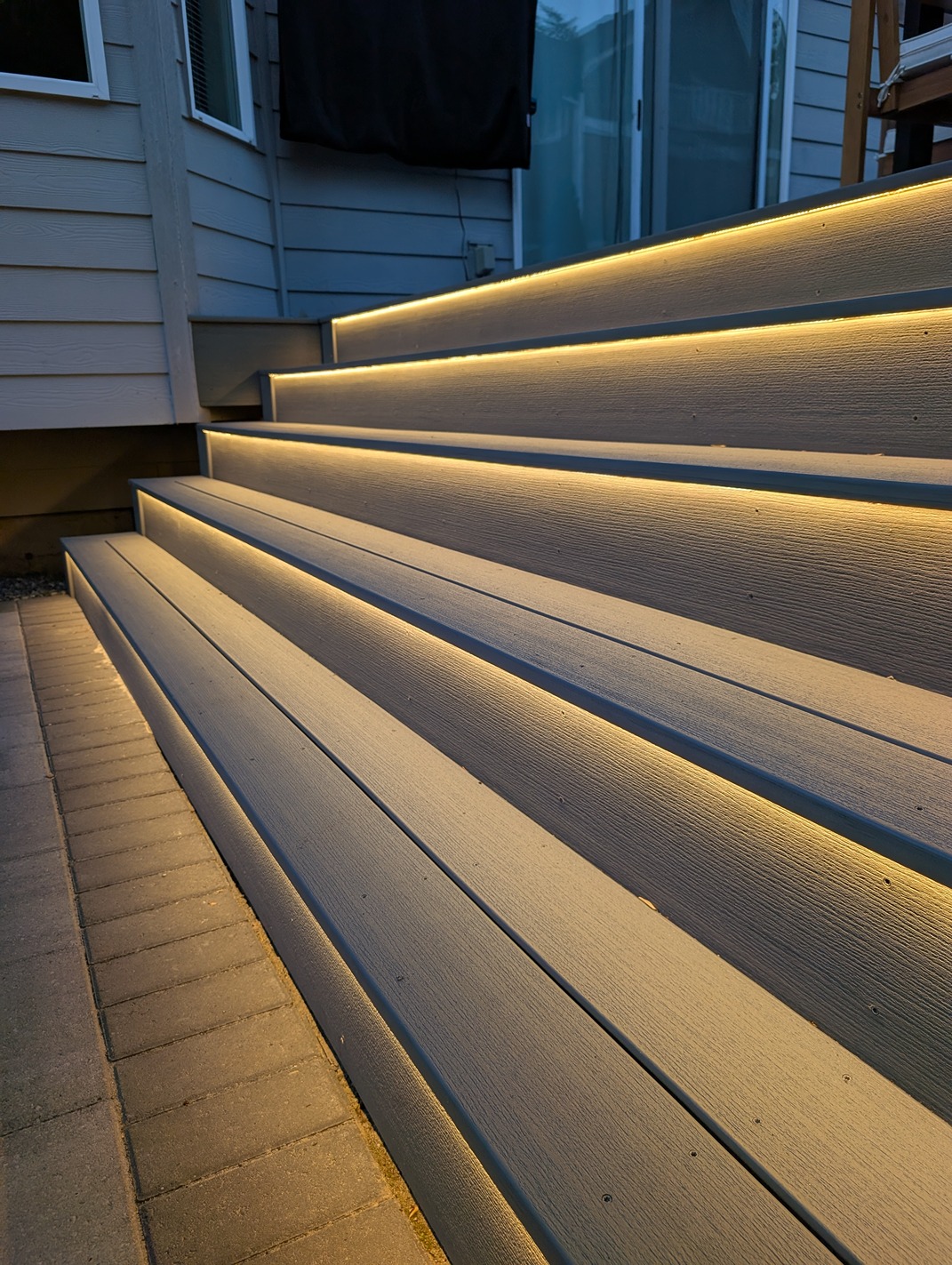 LED-lit composite deck stairs with warm riser lighting for safe nighttime access in a backyard