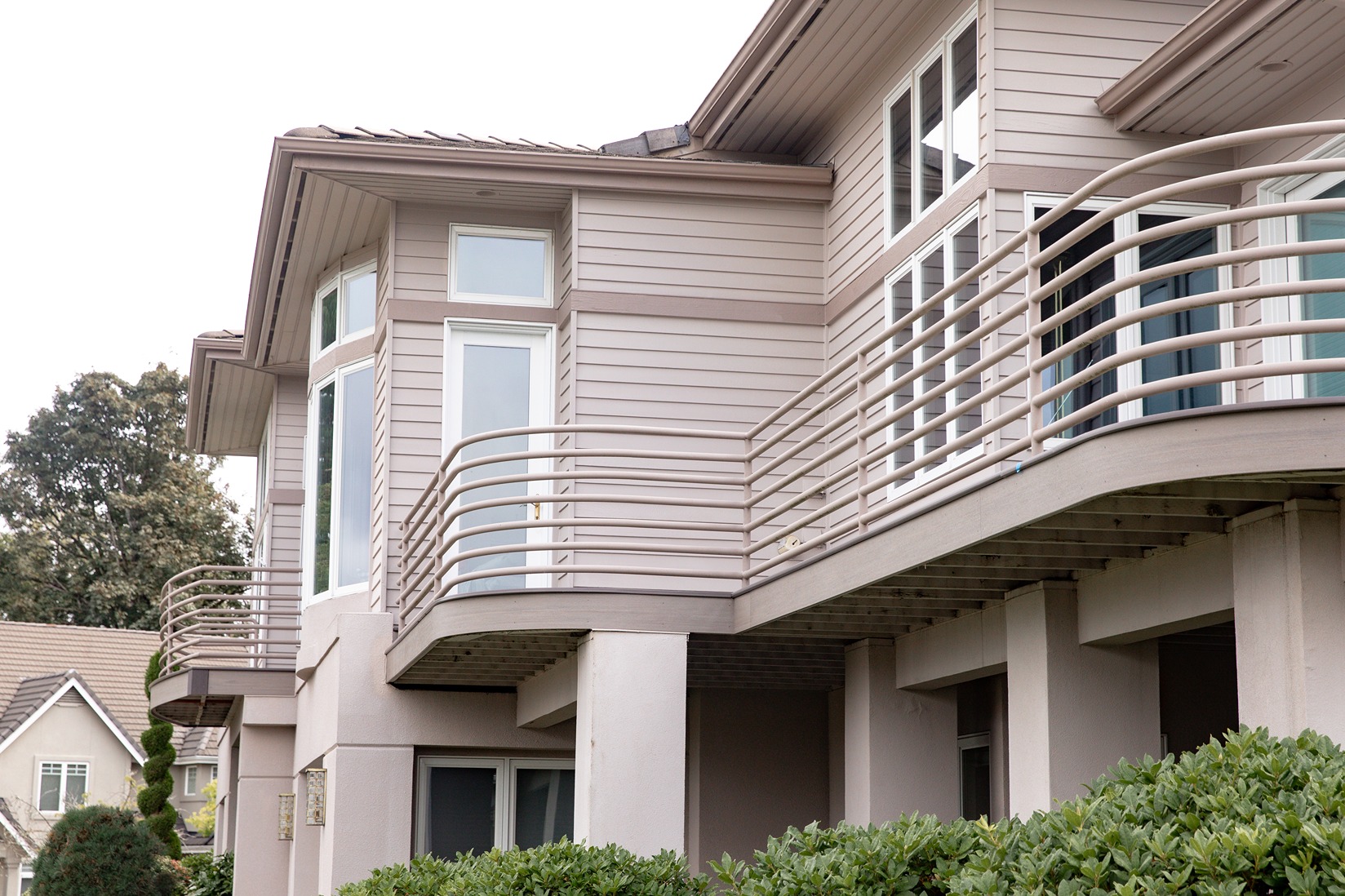Beige tubular aluminum railing with horizontal rods wrapping a curved second-story deck