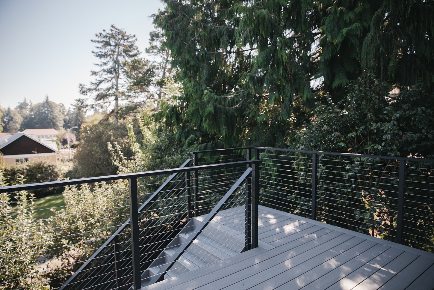 Horizontal cable deck railing with black aluminum posts on a gray composite deck and stairs (2)