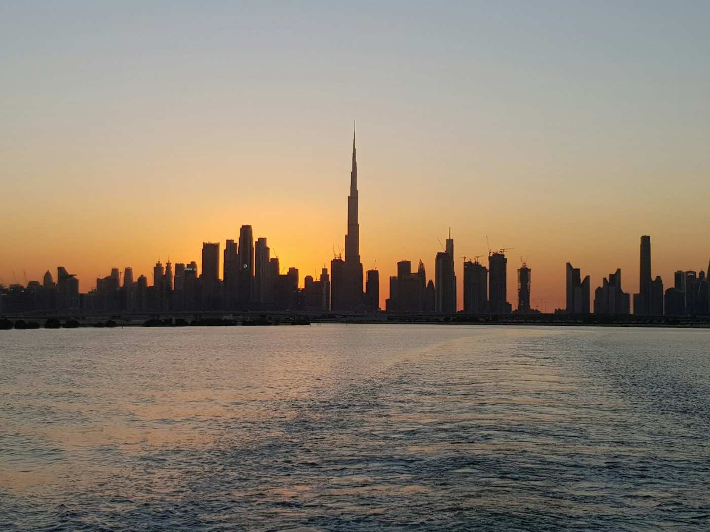 The Dubai skyline at sunset, seen across the water