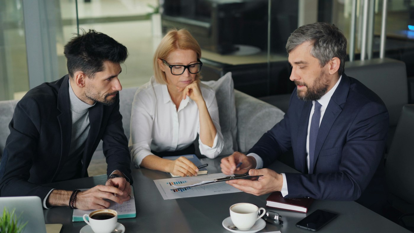 An adviser reviewing an investment plan with two clients