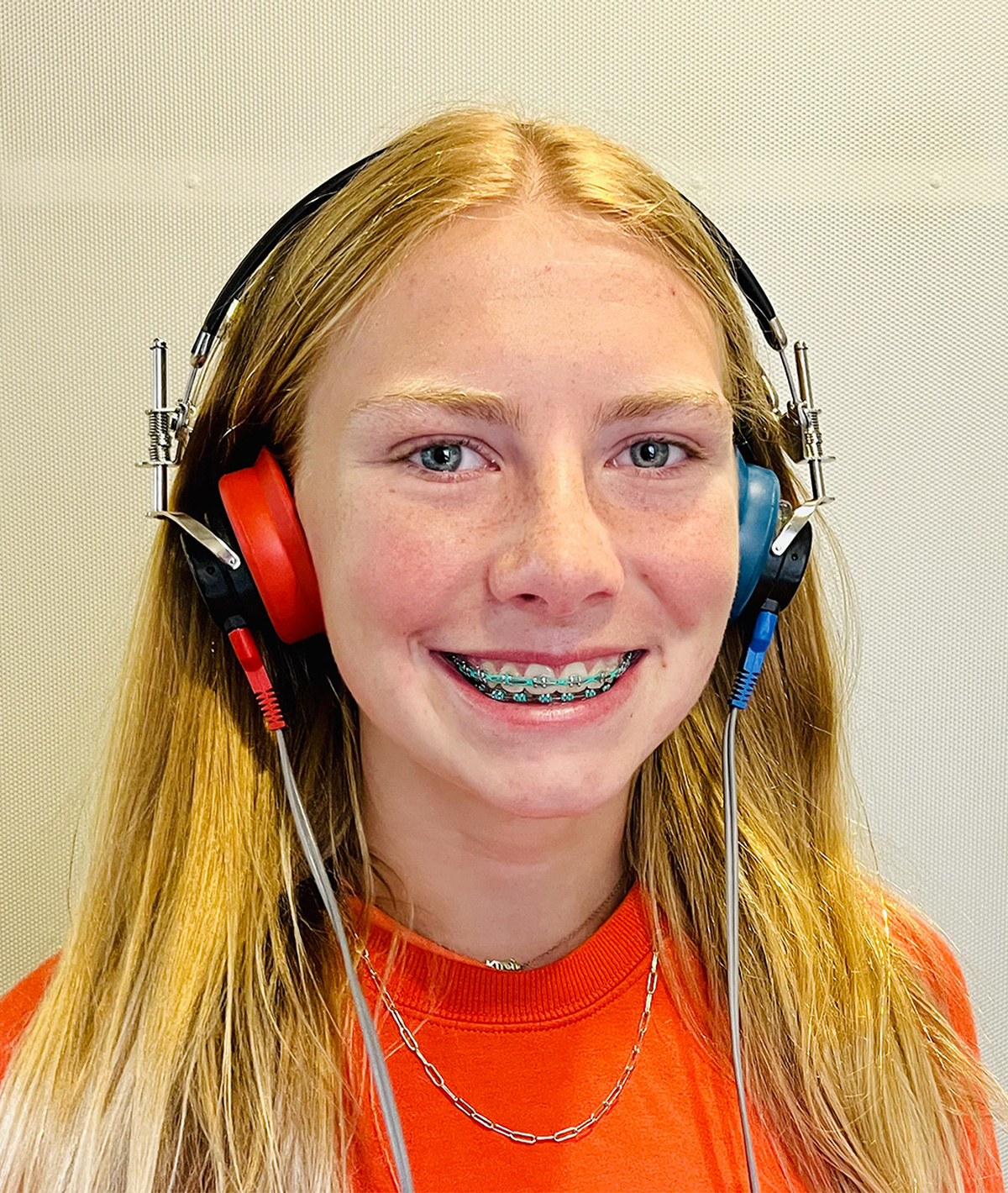 A young red haired girl wearing headphones used for CAPD testing.