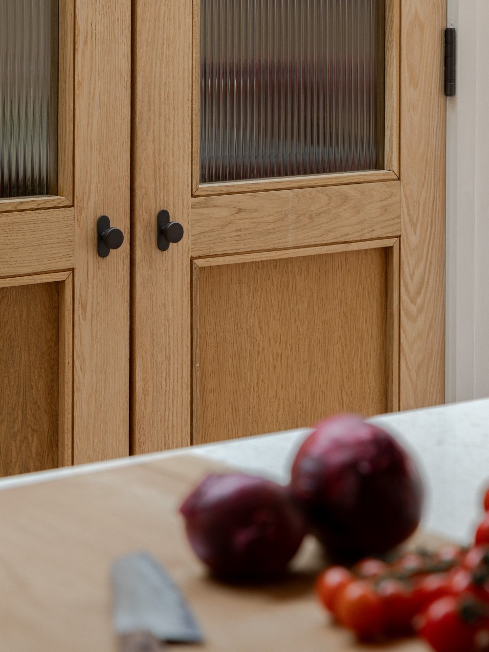 Close up detail of a custom oak pantry door with reeded glass in the Strata House kitchen design by London architects Benjamin Wilkes.