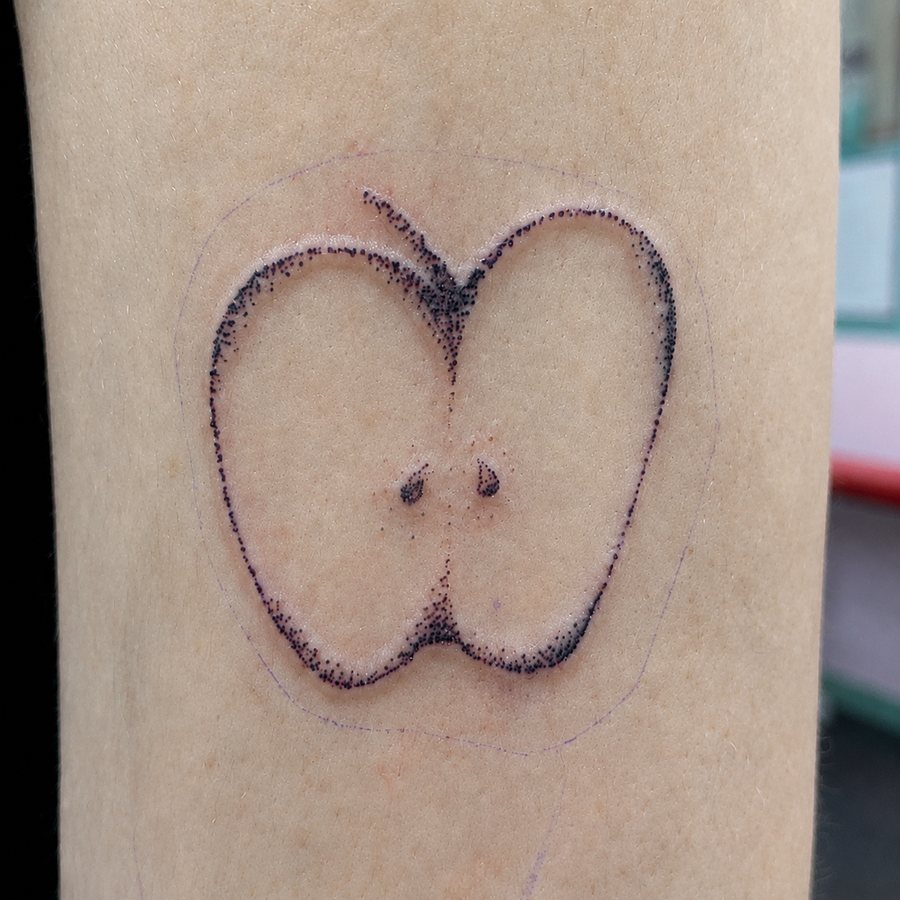 Fine-line apple outline tattoo with a stem