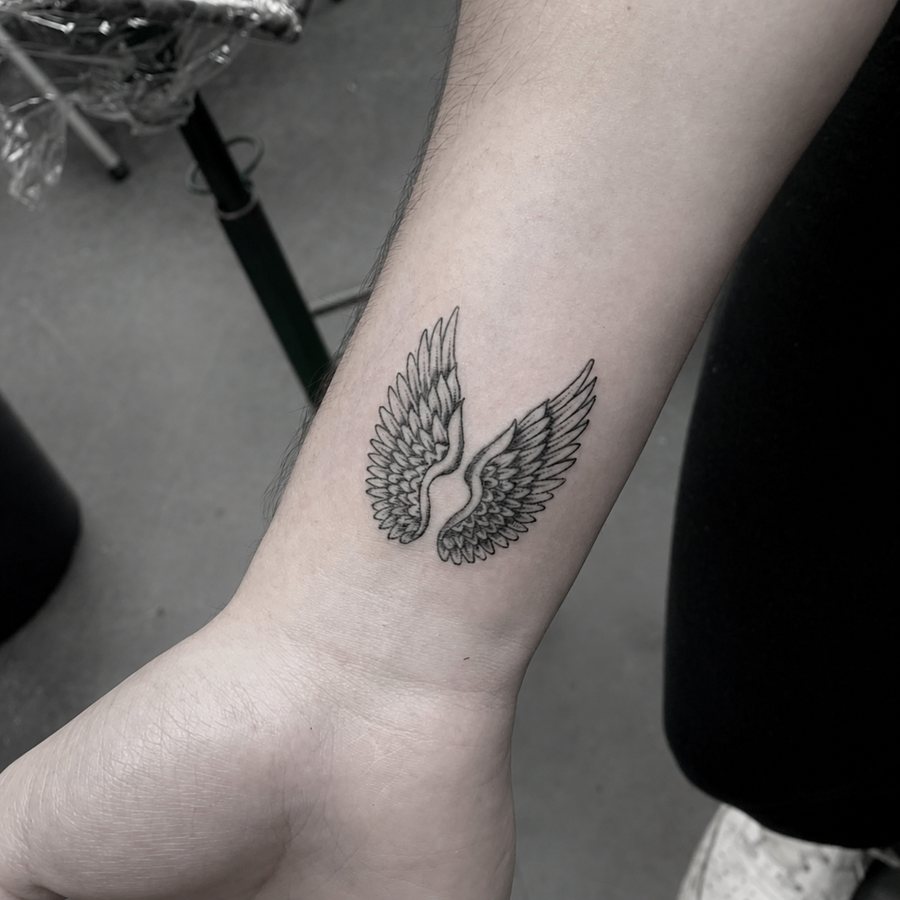 Black-and-grey swan tattoo with raised wings on a forearm