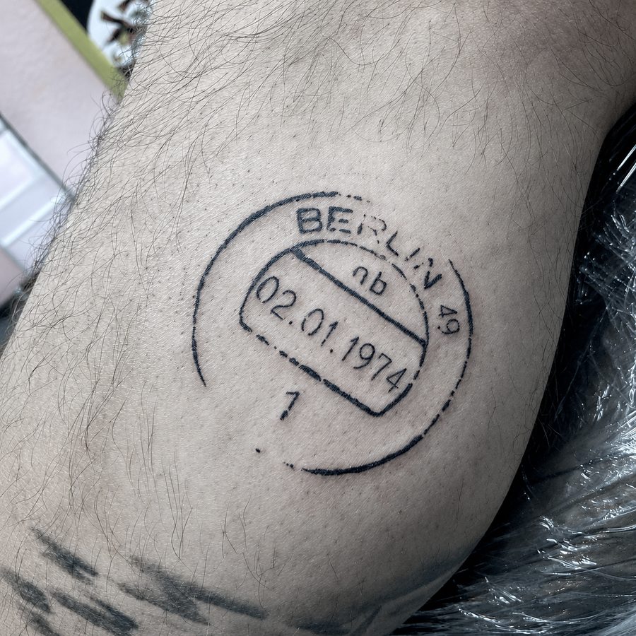 Fine-line Berlin date tattoo with a circular border