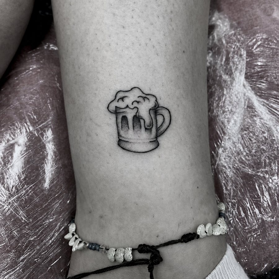 Small black beer mug tattoo on an ankle