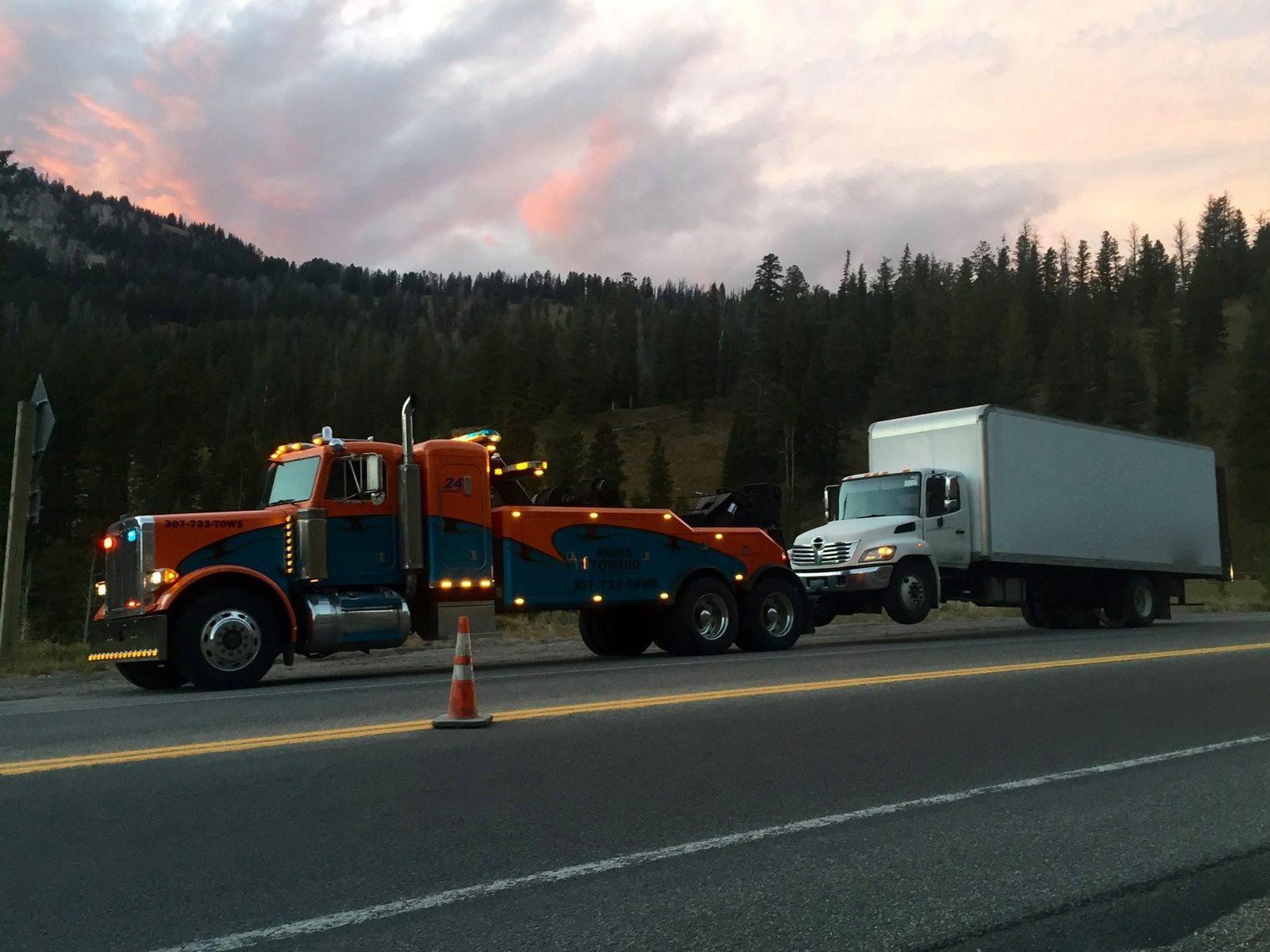 Ron's Towing heavy-duty wrecker towing a commercial truck over a mountain pass