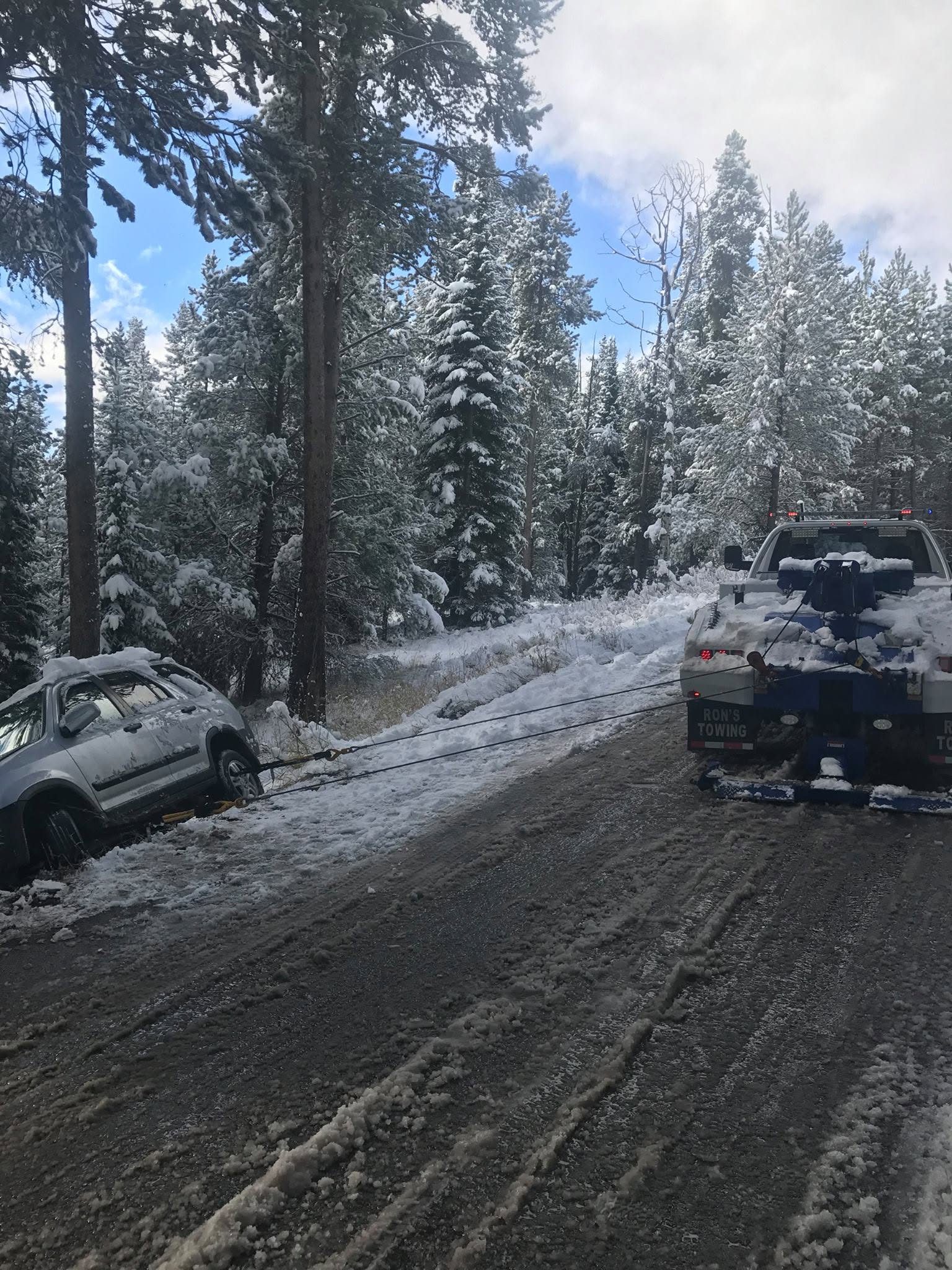 Ron's Towing truck arriving to help a car stuck on a snowy Jackson Hole lane