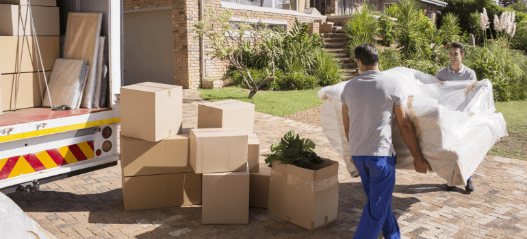 2 men carrying sofa to a house
