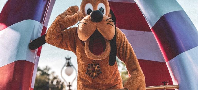 A Disney character called Pluto is waving at the camera.