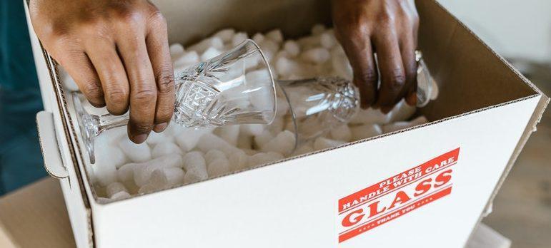 a guy packing glass in cardboard box