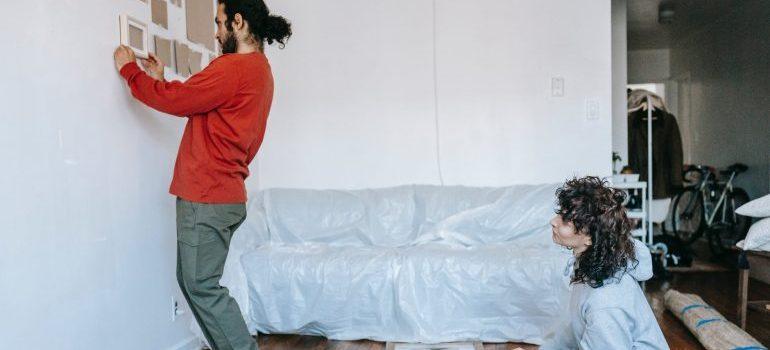 a man hanging photos on a wall