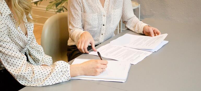 two women signing documents
