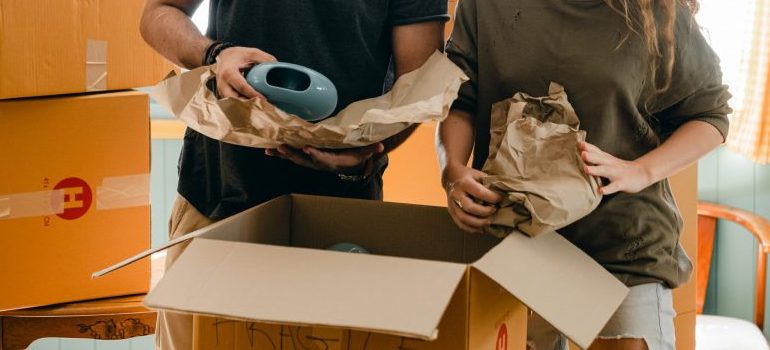a couple using packing paper, preparing items for the relocation
