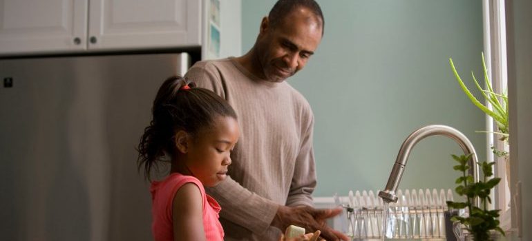 A father and daughter washing dishes together
