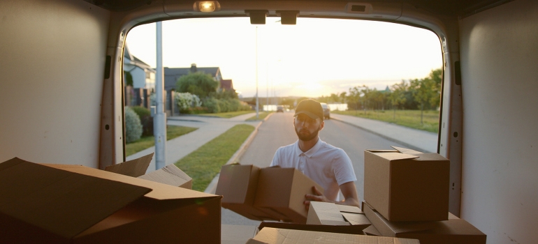 A man loading cardboard boxes into the vehicle