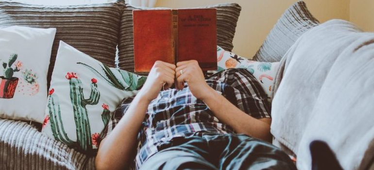 person laying down, resting, reading a book