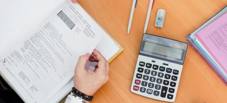 calculator, pens on the table, person looking at the papers
