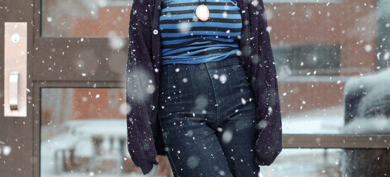 a woman standing on snowy street and thinking about the cheapest time to relocate in CA