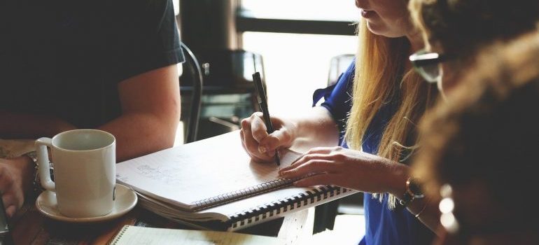 A business meeting where a girl is completing her commercial relocation checklist by informing everyone about the relocation.