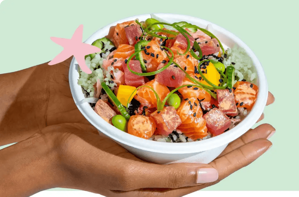 A fresh poke bowl with salmon, tuna, mango, edamame, and green onions on rice, topped with black sesame seeds.