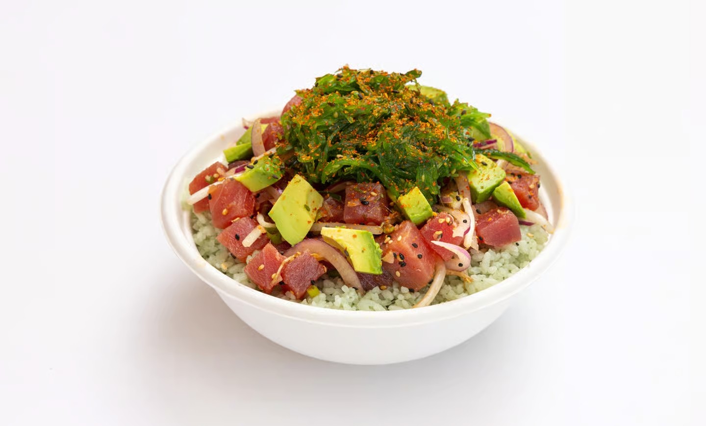 A poke bowl with diced tuna, avocado, onions, seaweed salad, and sesame seeds served over sushi rice.