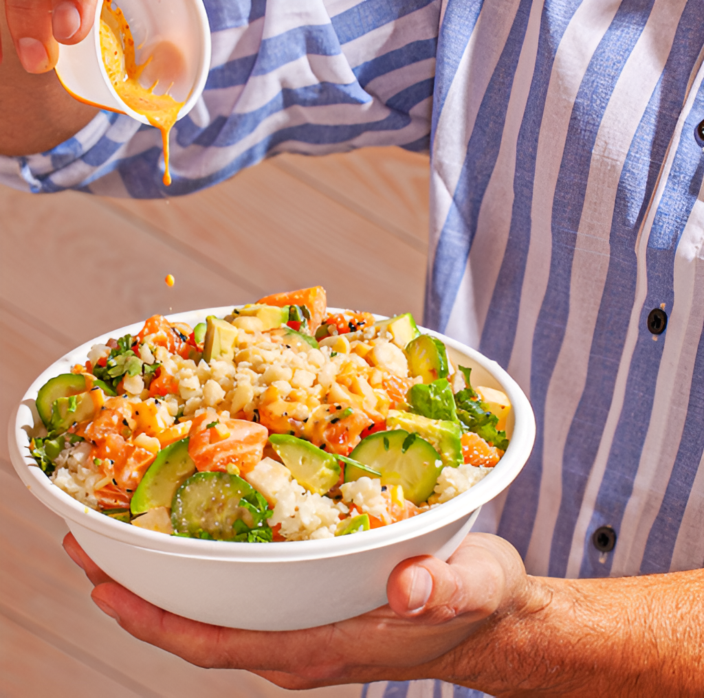 A man pouring the sauce into his poke bowl from Sweetfin catering.