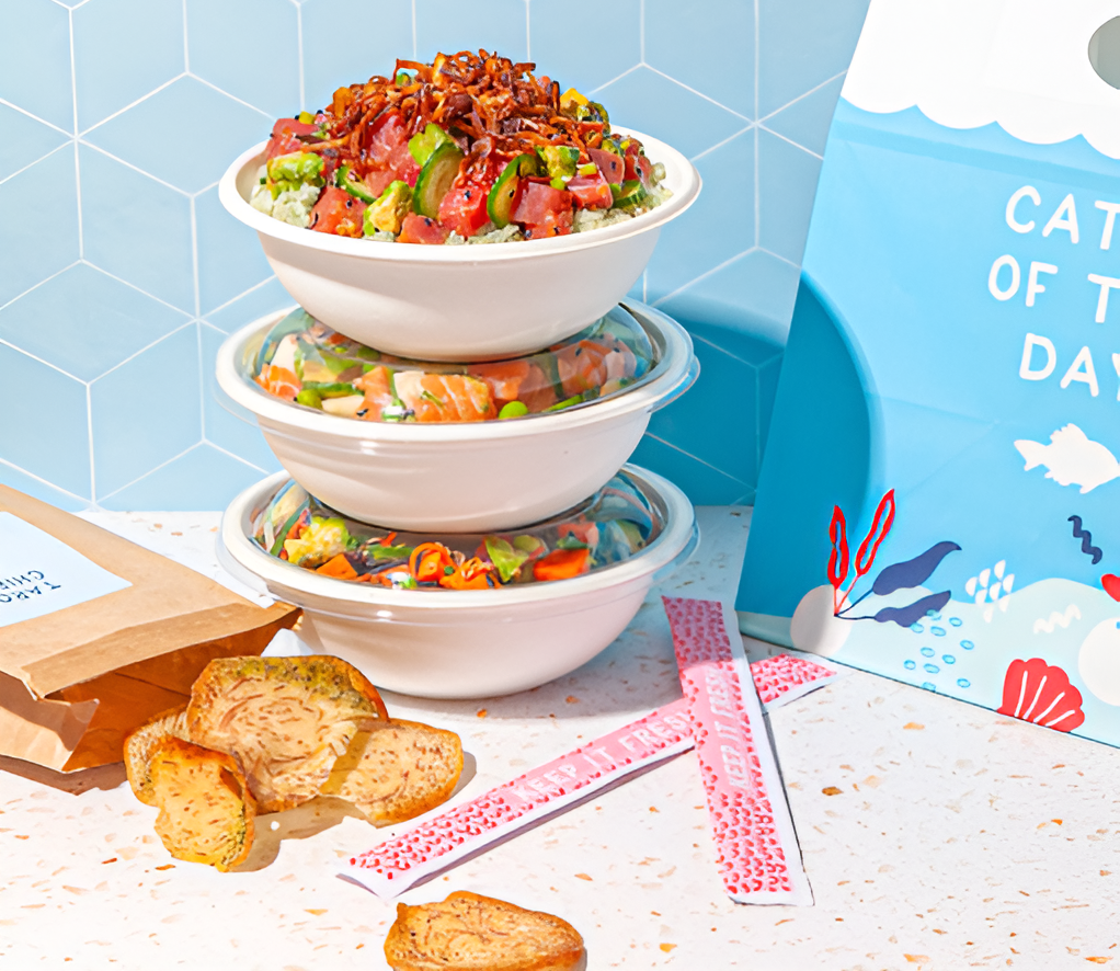 A stack of fresh poke bowls from Sweetfin was kept at an outdoor event along with some chips.