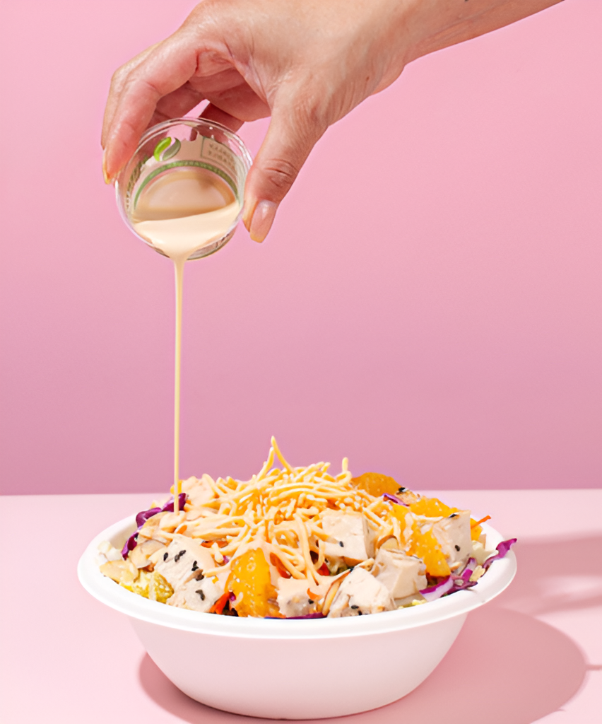 A person pouring the sauce into a poke bowl made at Sweetfin.