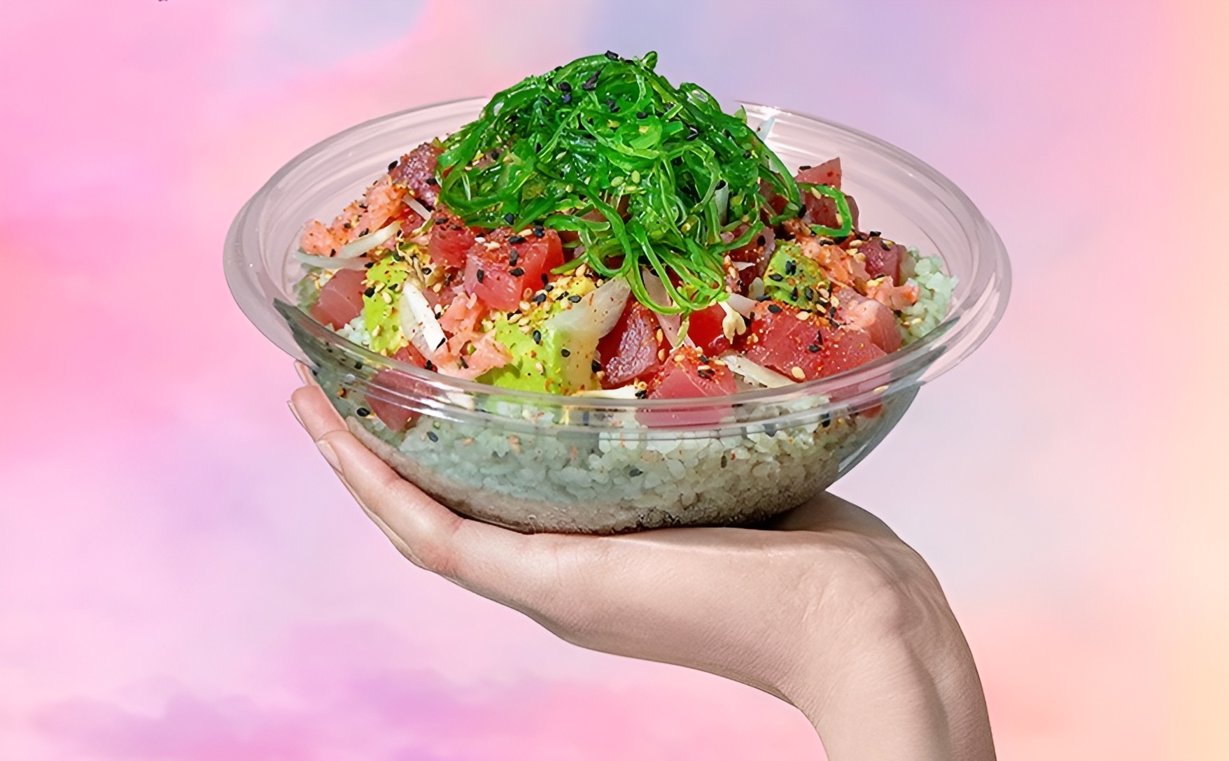 A Sweetfin veg pokebowl being held against a pastel pink backdrop.