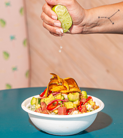 A picture of fresh lemon squished on a ready Poke Bowl from Sweetfin.