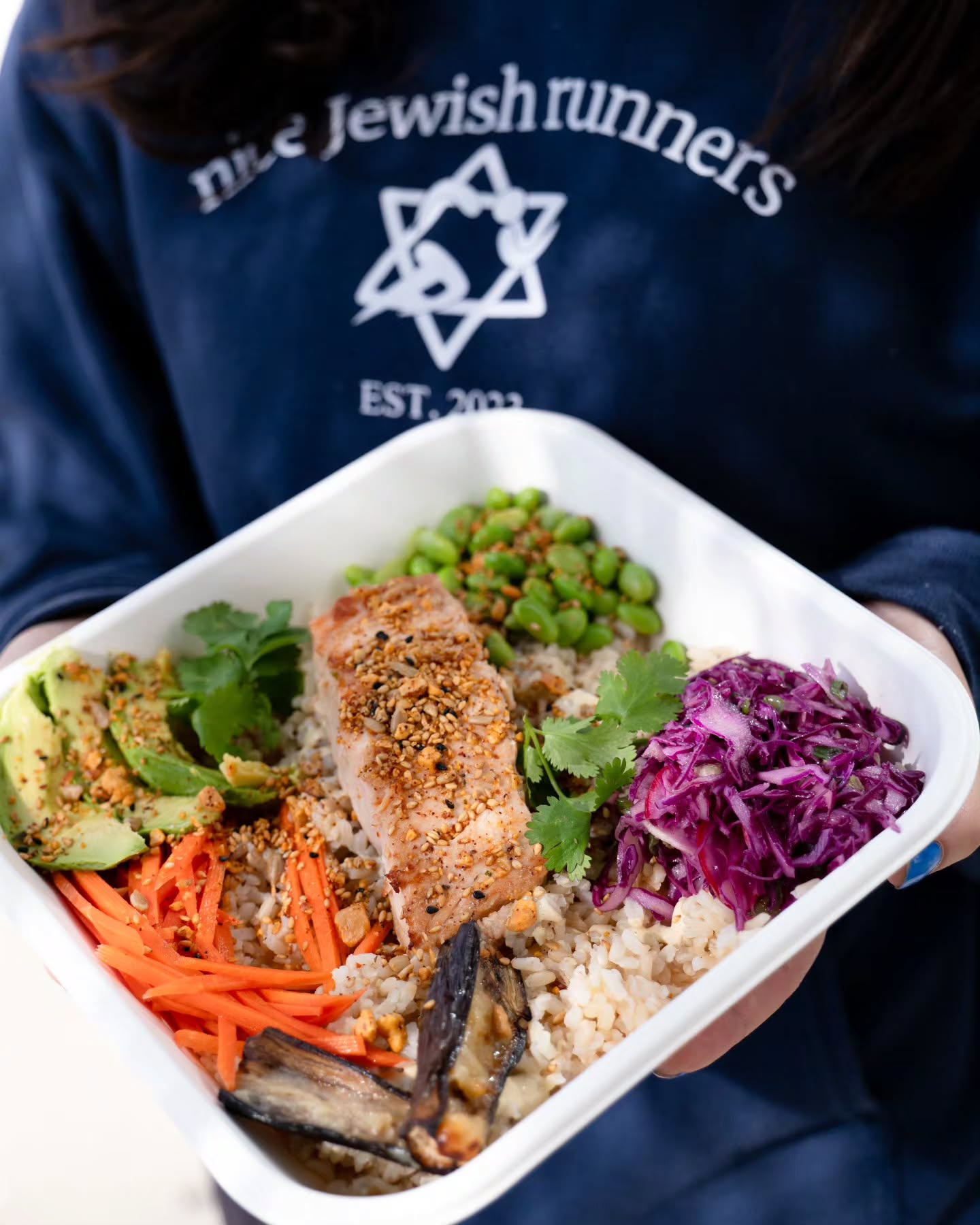 A member of a Jewish running club holding a protein-rich bowl from Sweetfin.