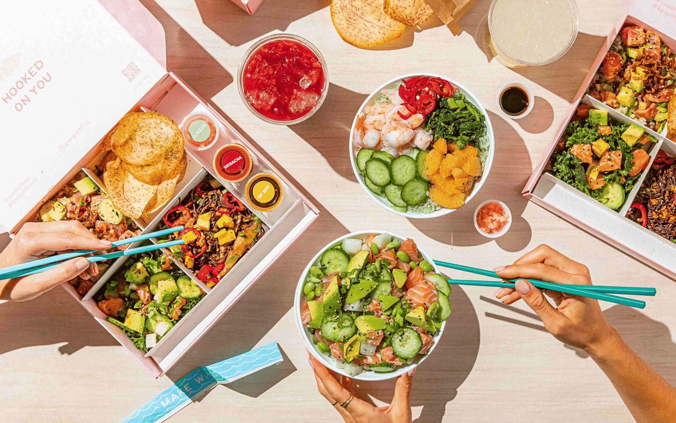 Sweetfin poke bowls and salads served with fresh ingredients, avocado, salmon, vegetables, sauces, and crispy toppings in a bright dining setting.
