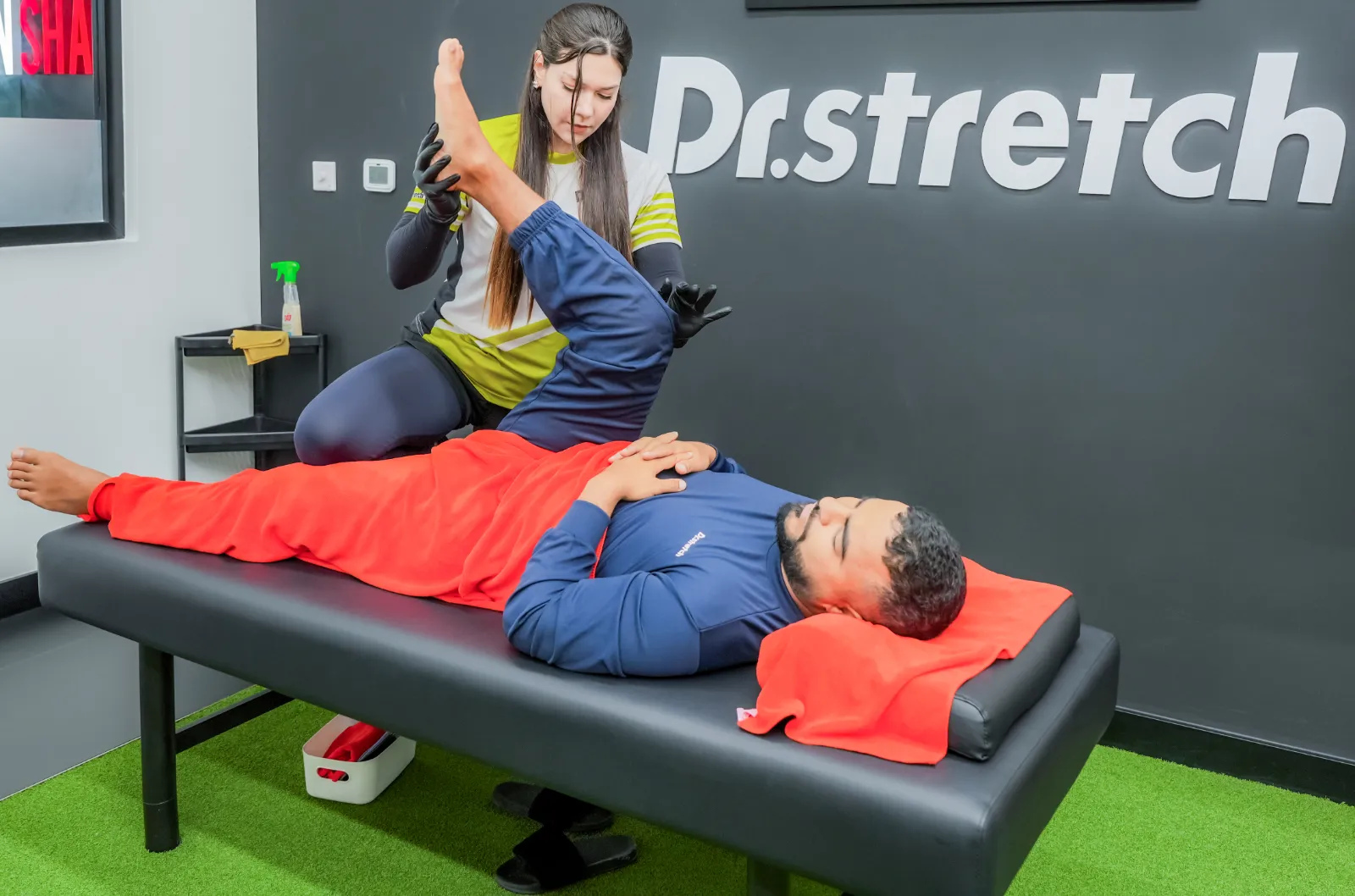 Dr.stretch trainer performing an assisted hamstring stretch on a client in a UAE studio