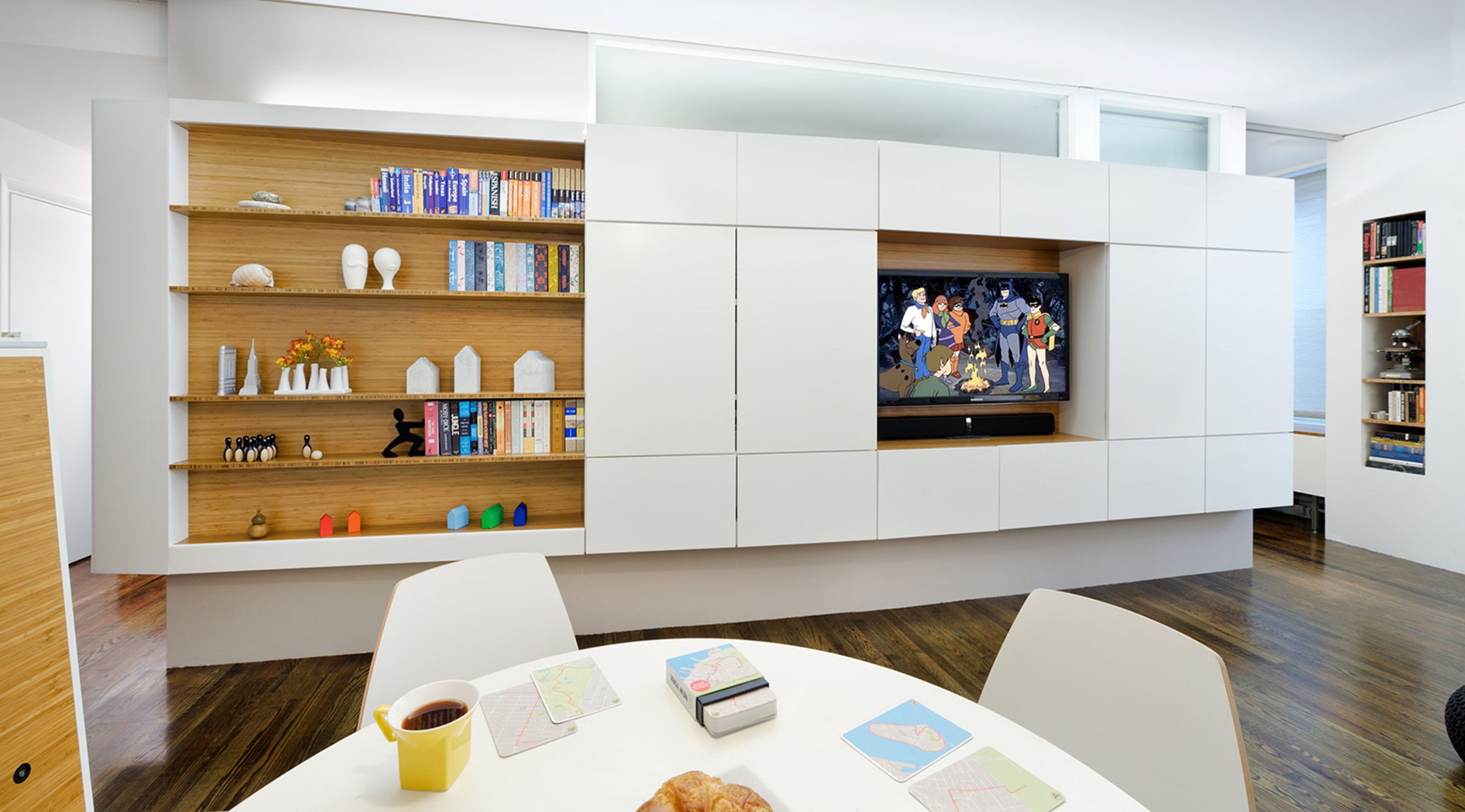 Inspired by the Flatiron Building four blocks away, a floating, wedge‑shaped storage object was inserted down the keel of the living room