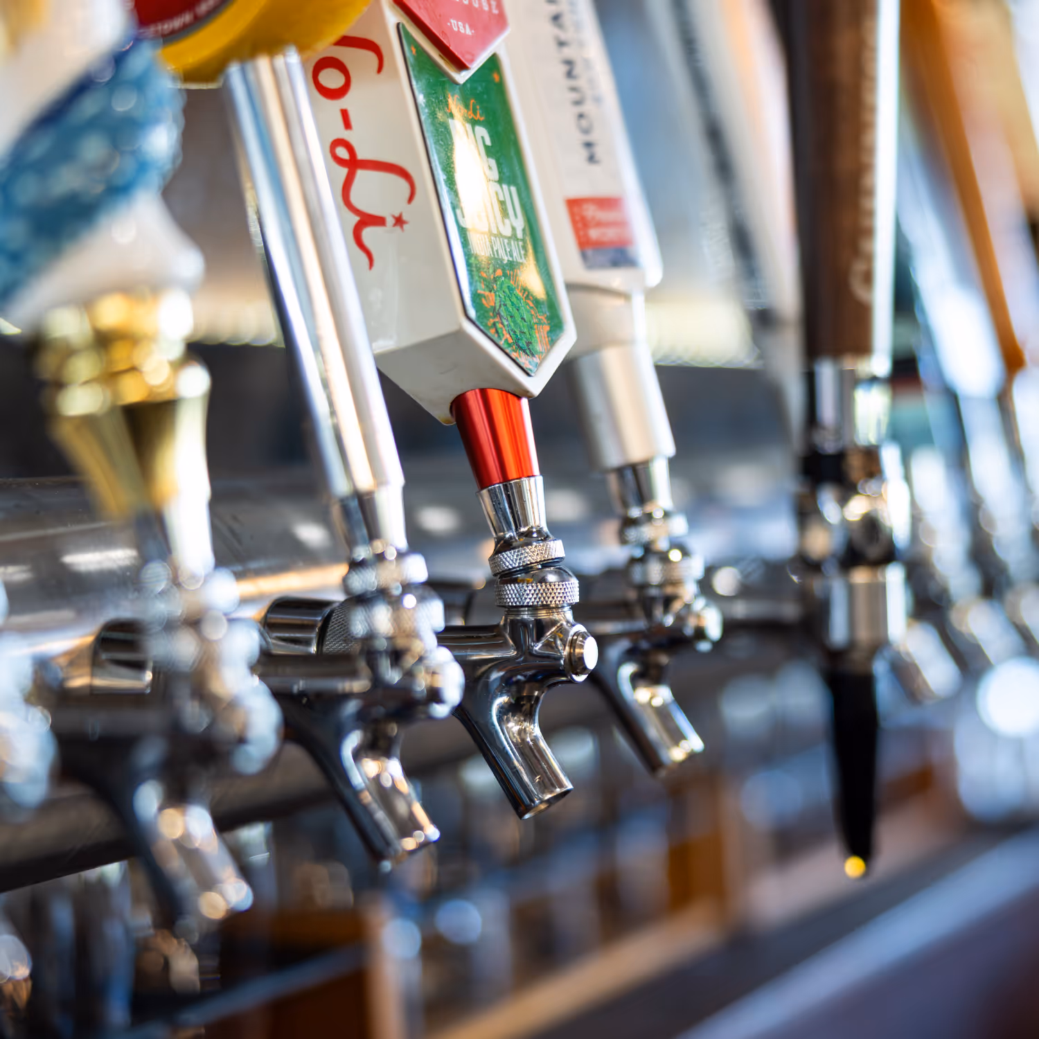 Close up photo of the spouts on a line of restaurant beer taps