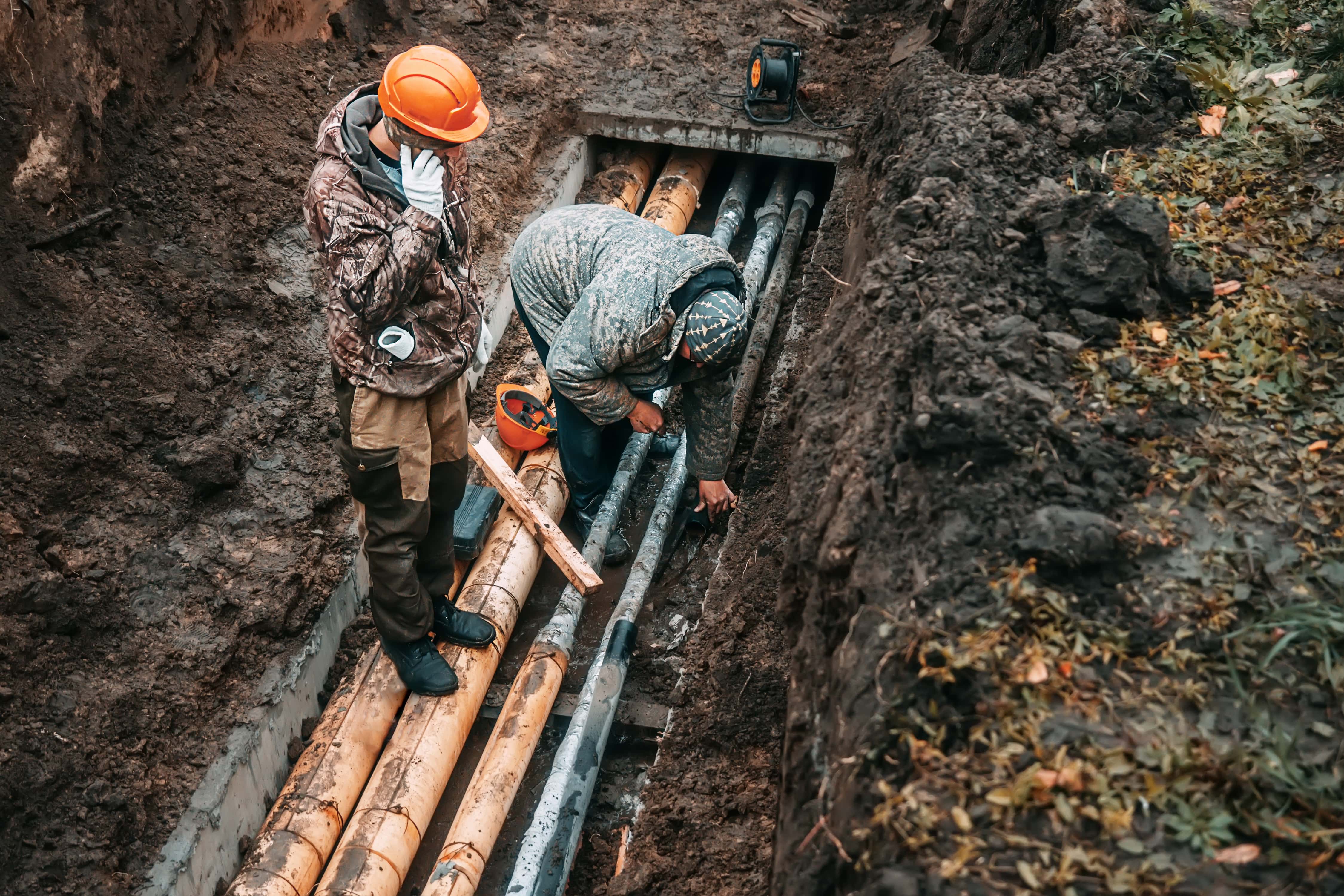 Workers inspecting an underground pipe